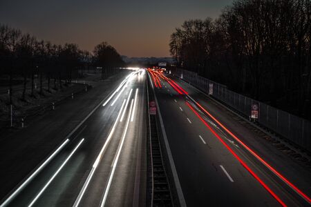 Highway leading in to the alps by sunset. You can see light trails from the cars and the last...