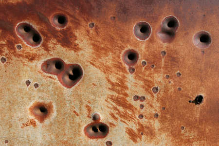 background - side of a rusting metal fridge with bullet holesの写真素材