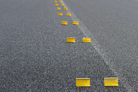 road work - abstract background with temporary yellow markings on fresh pavement. shallow depth of field with focus on first pair of markers.の写真素材