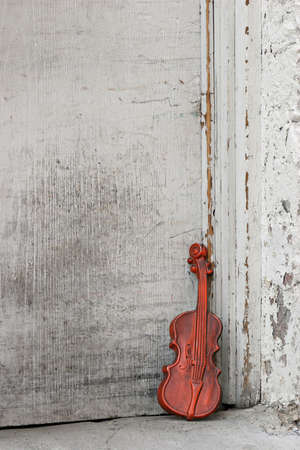 toy or makeshift violin outside, leaning against an old door.の写真素材
