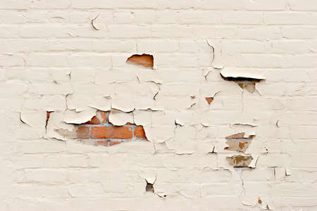 background with a red brick wall revealed through the peeling paintの写真素材