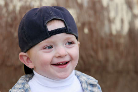 cute young boy smiling against light brown backgroundの写真素材