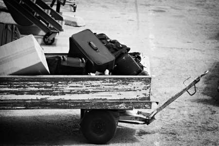 lost luggage sitting in an old wagon on the tarmac, converted to bw with focus on baggageの写真素材