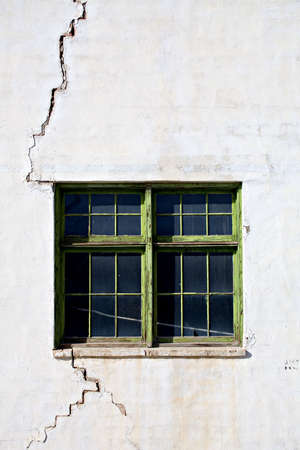 cracked wall with a green window on an old abandoned workshopの写真素材
