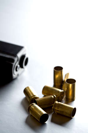 bullet casings with gun on brushed metal. shallow dof, focus on front bullet.の写真素材