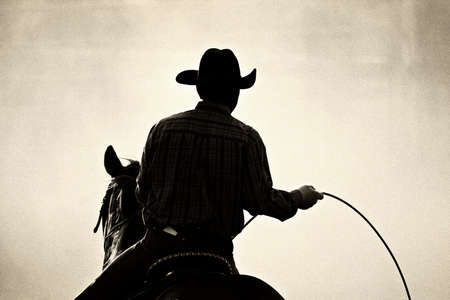 cowboy at the rodeo - shot backlit against big cloud of dust, converted with added grainの写真素材