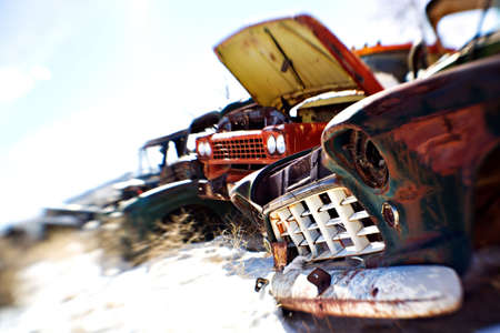 old cars in the snow at a rural junkyard. limited depth of field with focus on front grill. legal note - license plate heavily modified.の写真素材