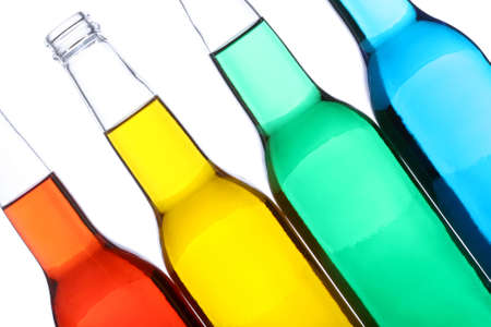 bottles with red, yellow, green, and blue liquids closeup isolated on whiteの写真素材
