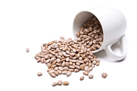 spill the beans - pinto beans spilled from white cup, isolated on whiteの写真素材