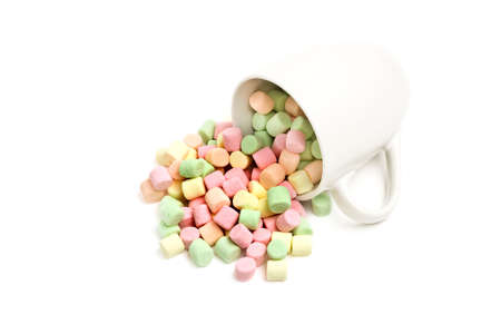 marshmallows being spilled from a white cup, closeup isolated on whiteの写真素材