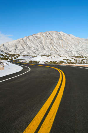 road winding through winter mountains with clear blue sky in Northern Wyomingの写真素材