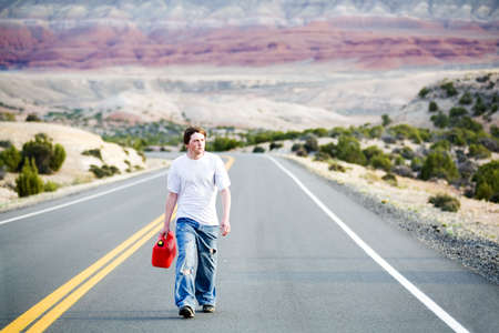 teenager out of gas, walking down rural mountain road with gas canの写真素材