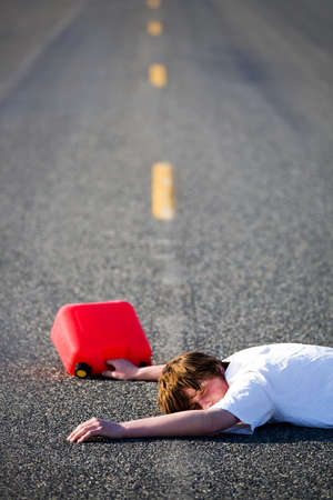 out of gas - teen with empty gas can lies dead in the middle of the roadの写真素材