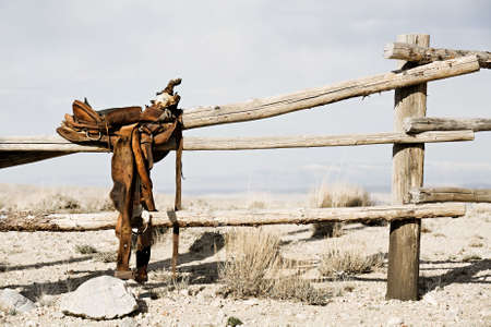 ranch scene - saddle on rural fence, vintage worn saddle in the dry and barren countrysideの写真素材