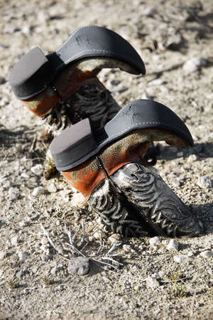 vintage cowboy boots buried upside down in the dirtの写真素材