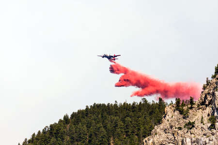 firefighting aircraft dumping red fire retardant chemical over forest during Montana fire fighting...