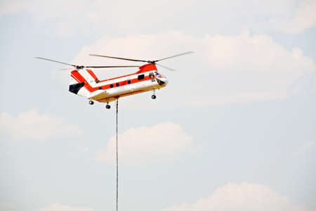 helicopter heavy twin rotor aircraft hovering above field lifting cargoの写真素材