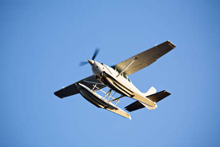 seaplane or floatplane in flight against blue sky, late sunの写真素材