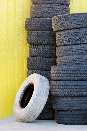 tires stacked up against a yellow wallの写真素材