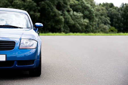 sports car - modern blue coupe on road, focus on headlight with ample copyspaceの写真素材