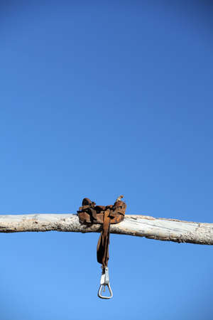 saddle on a wooden post against clear blue skyの写真素材