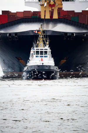 tugboat pulling a freighter on the Elbe river in Hamburg Harbor, Germanyの写真素材