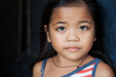 Asian child portrait - young girl from the Philippines against wall - natural lightの写真素材