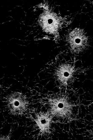 bullet holes in glass - authentic bullet holes from handgun - background or design element isolated on blackの写真素材
