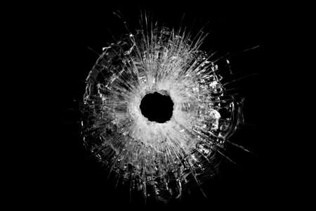bullet hole in glass closeup and isolated on solid black. Actual gunshot from a .44 handgun.の写真素材