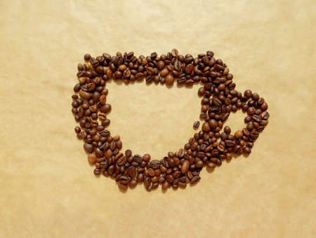 Cup made of coffee beans on a brown craft paper backgroundの写真素材
