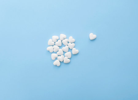 White pills in the shape of hearts on a pastel blue backgroundの写真素材