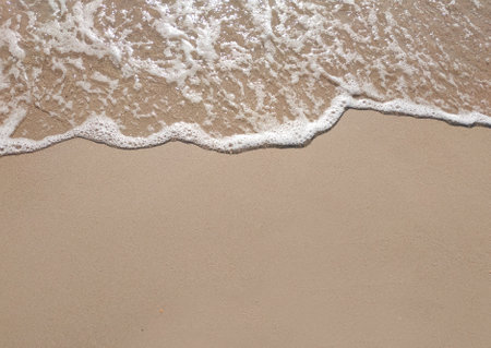 White foamy wave on the beach sand. Top view. Marine texture backgroundの写真素材