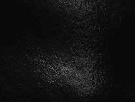 Black foil background with highlights and uneven textureの写真素材