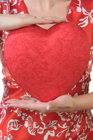Young woman in red holds a red heart opposite the bust. Without of faceの写真素材