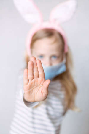 blonde girl in a striped jacket, on a bright background, with rabbit ears on her head, holding a basket of eggs, smilingの写真素材