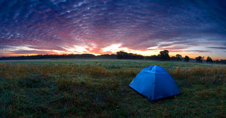 Sunshine rising over a tent in the wildernessの写真素材