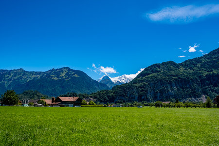 Meadow landscape with a view of a farm and mountainsの写真素材