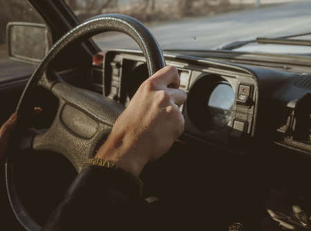 A mans hand on the steering wheel of a classic car