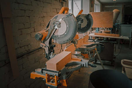 Dual compound-miter saw. An variety of tools sitting on workbenches inside of a woodworking shop