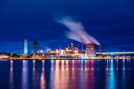 A panoramic view of the pipes and cooling towers of the CHP. Industry district at night, reflection in water.の写真素材