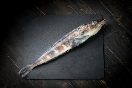 Frozen mackerel icefish on a black stone background. High quality photo