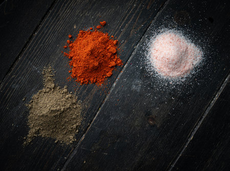 Black pepper, red pepper, salt on a black wooden background. Copy space.の写真素材