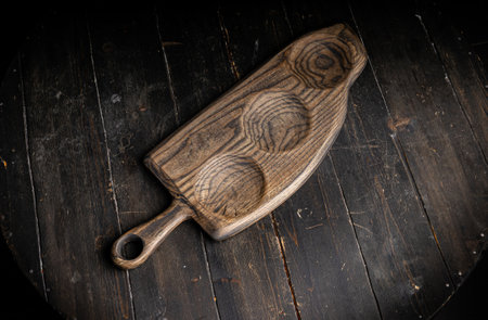 Empty three-compartment serving board made with hardwood on the old rustic table, top view.の写真素材