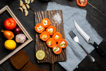 Salmon rolls with cream cheese and pistachios on a wooden cutting board. Luxury catering. Top view.の写真素材