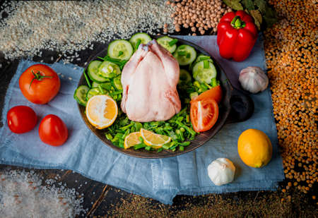 Raw cornish chicken. Fresh chicken with tomatoes, cucumbers, dill, parsley and spices.の写真素材