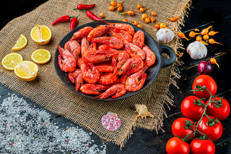 Raw shrimps with pepper, lemons in a wooden plate. Seafood. Top viewの写真素材
