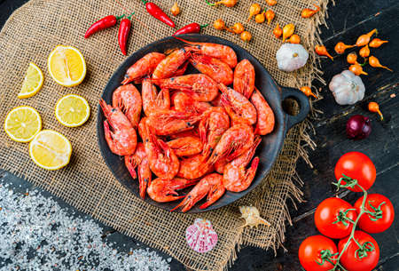 Raw shrimps with pepper, lemons in a wooden plate. Seafood. Top viewの写真素材