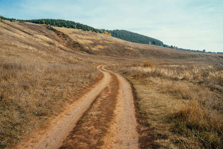 Dirt road in the steppe. Landscape with a wide dirt road going through the steppe up to the hills.の写真素材