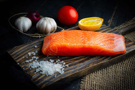 Fresh raw chilled salmon fillet on a woodencutting board. Healthy eating, seafood recipe ingredient.の写真素材