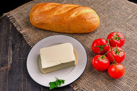 Fresh tasty butter on a kitchen table. A piece of butter on a white plate.の写真素材